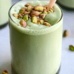 A close-up of a hot pistachio matcha latte with matcha dusting