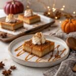 Pumpkin pie bars topped with whipped cream and caramel