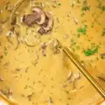 A bowl of rich cream of mushroom soup topped with fresh herbs