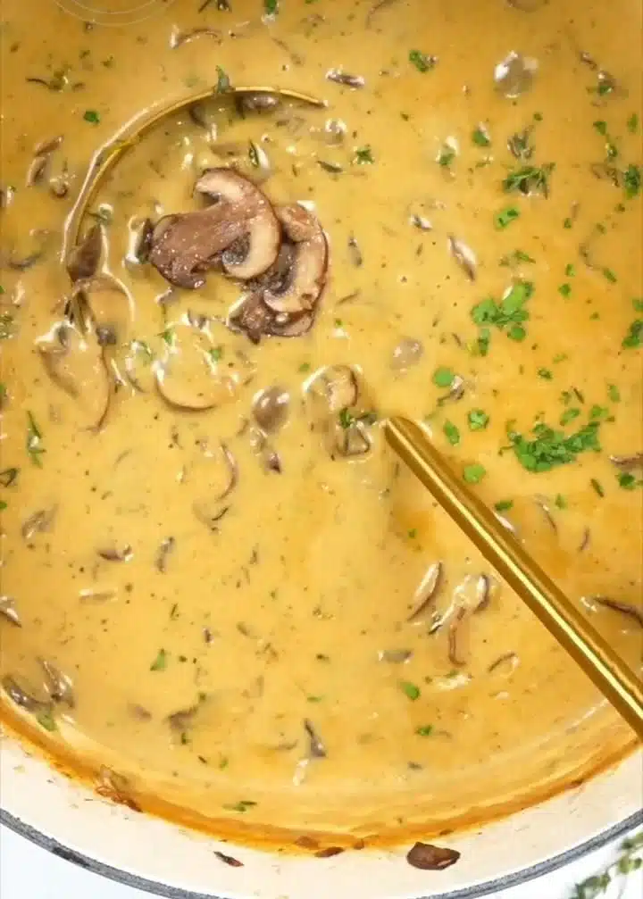 A bowl of rich cream of mushroom soup topped with fresh herbs