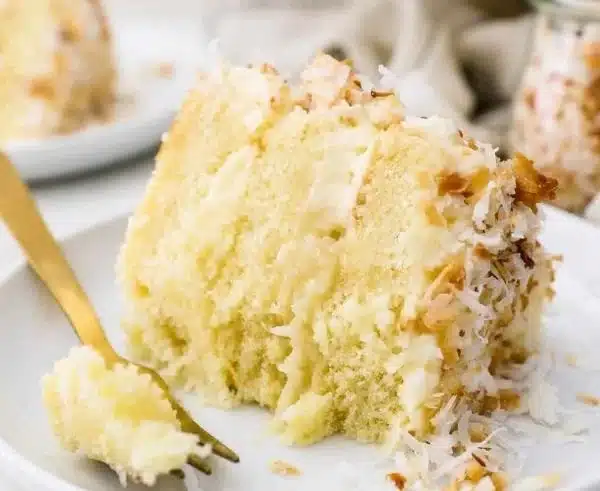 Deliciously baked Coconut Cake topped with fresh coconut flakes.