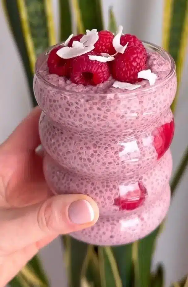 Raspberry chia pudding topped with fresh berries in a glass bowl